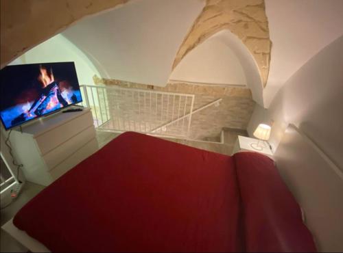 Schlafzimmer mit einem roten Bett und einem TV in der Unterkunft Il loft del vico in Galatone