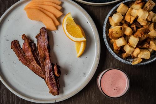 a plate of food with bacon and orange slices at The Magnolia Hotel & Spa in Victoria