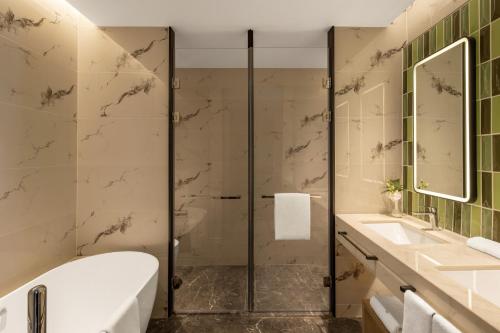 a bathroom with a shower and a tub and sink at Holiday Inn & Suites Qingdao Jinshui by IHG in Qingdao