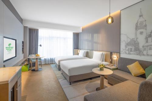 a hotel room with a bed and a couch at Holiday Inn & Suites Qingdao Jinshui by IHG in Qingdao