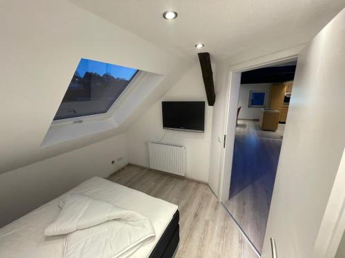 Habitación pequeña de color blanco con cama y TV de pantalla plana. en Appartement Linde, en Olpe