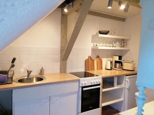 een keuken met witte kasten en een wastafel bij Loft "im Alten Pfarrhaus" in Neuruppin