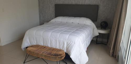 uma cama com um edredão branco e uma cadeira num quarto em Garden View 2 Dormitorios con Jardín y Parrillero hasta 7 personas em Punta del Este