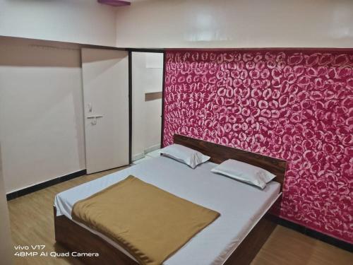 a bedroom with a bed with a red wall at Sai Ganesh Guest House in Shirdi