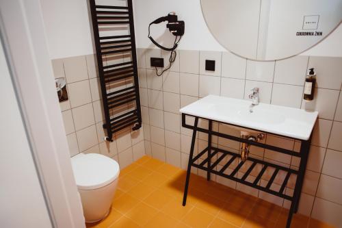 a bathroom with a toilet and a sink and a mirror at Cukrownia Żnin in Żnin