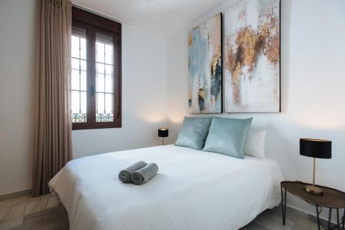 ein Schlafzimmer mit einem großen weißen Bett und einem Fenster in der Unterkunft Magno Apartments Requena in Sevilla
