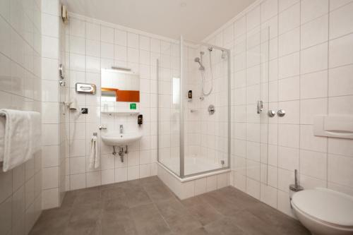 a bathroom with a shower and a toilet and a sink at Hotel Omega in Moers