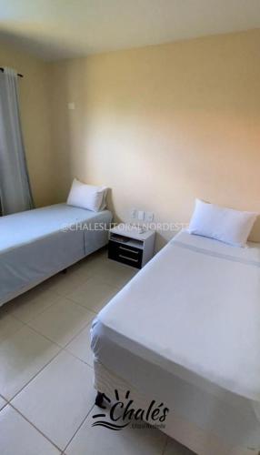 two beds in a hotel room with white sheets at Chalé com piscina privada vista mar-Zumbi-RN in Rio do Fogo