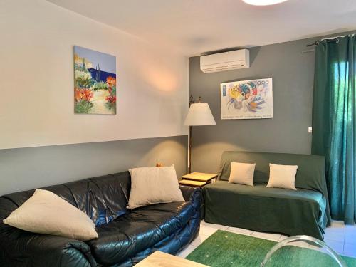 a living room with a leather couch and a table at Blagnac : appartement T2 avec jardin, parking et climatisation in Blagnac