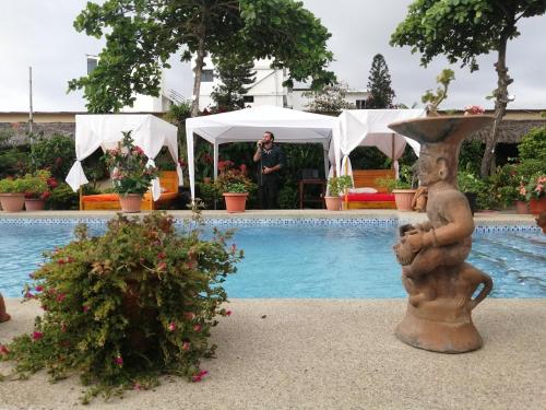 a man standing next to a swimming pool with a statue at The Cottages by the Sea in San Clemente