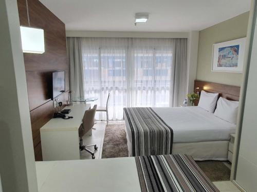 a hotel room with a bed, chair and a window at Fusion Hplus Express + in Brasília