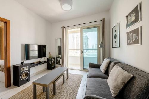 een woonkamer met een bank en een tv bij Beautiful Marina Views One Bedroom Apartment with two balconies in Dubai