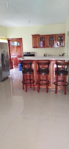 a kitchen with a counter with chairs and a refrigerator at Royal Vybez Vacation Homes in Spanish Town