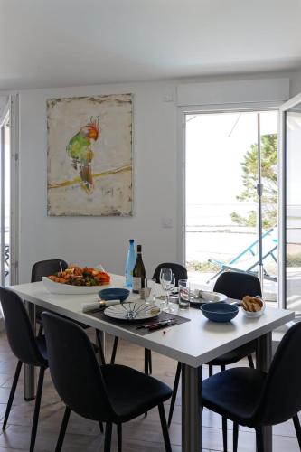 a table with chairs and a plate of food on it at Face à la mer - 50 m de la plage des homardiers in La Guérinière