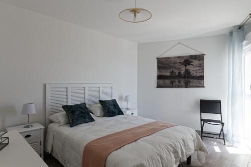 a white bedroom with a bed and a chair at Superbe appartement neuf face plage sur l ile de Noirmoutier in La Guérinière