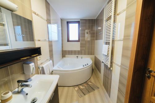 a white bathroom with a tub and a sink at Popas Dumbravita in Răstoaca