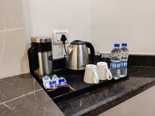 eine Theke mit Kaffeemaschine, Tassen und Wasser in der Unterkunft Hotel D SilverLeaf in Lucknow