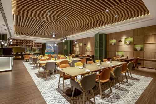 a restaurant with tables and chairs in a room at Holiday Inn & Suites Qingdao Jinshui by IHG in Qingdao