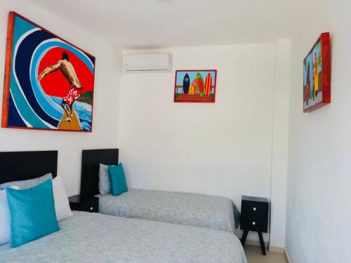 a bedroom with two beds and a painting on the wall at The Beach Break Hotel El Zonte in El Zonte