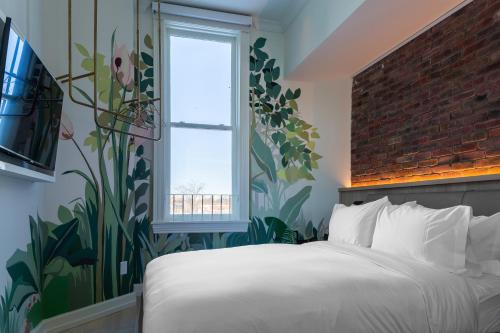 a bedroom with a white bed and a brick wall at Gladstone House in Toronto