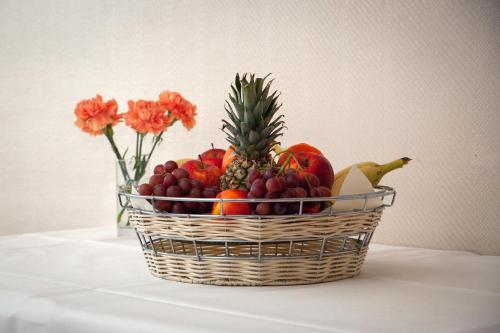 a basket of fruit on a table with a vase of flowers at Hotel Omega in Moers