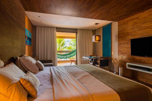 a bedroom with a large bed with a flat screen tv at Carmel Charme Resort in Aquiraz