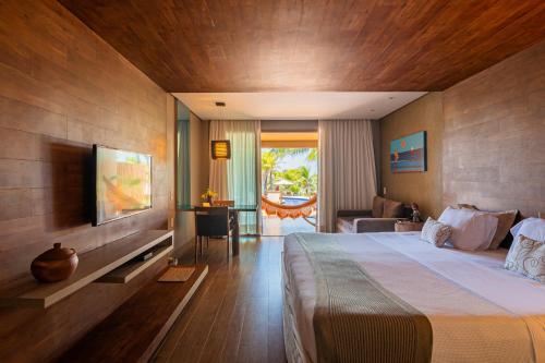 um quarto de hotel com uma cama grande e uma televisão em Carmel Charme Resort em Aquiraz