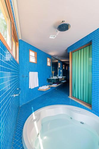 a blue tiled bathroom with a tub in a room at Carmel Charme Resort in Jacaúna