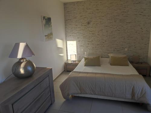 - une chambre avec un lit et un mur en briques dans l'établissement VILLAS-Piscine les MIMOSAS, à Fréjus