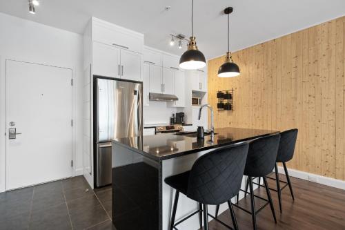 a kitchen with a black counter and black stools at INITIAL -CLASSE S- Centre-ville de Québec +stationnement in Quebec City
