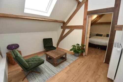 a living room with a green chair and a table at B&B 't Burreken in Schorisse