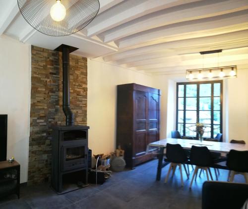 ein Esszimmer mit einem Tisch und einem Holzofen in der Unterkunft Grand gîte au coeur d'un charmant village in Miglos