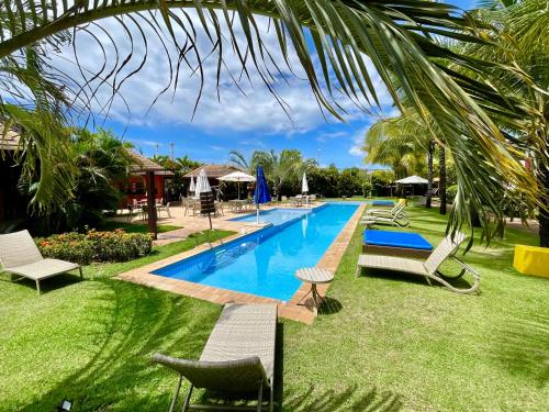 uma piscina num resort com espreguiçadeiras em Duplex aconchegante Cond Reserva Praia do Forte em Mata de São João