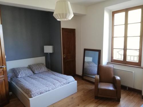 sypialnia z łóżkiem, krzesłem i lustrem w obiekcie Grand gîte au coeur d'un charmant village w mieście Miglos