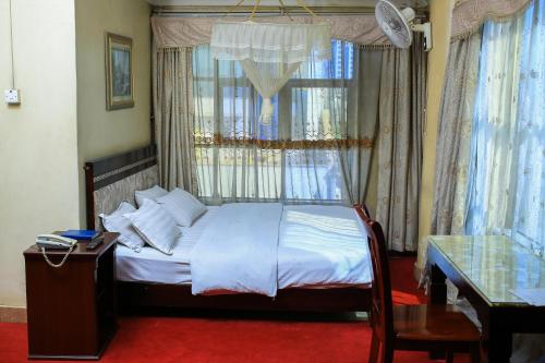 a bedroom with a bed with a window and a table at Steric Hotel Kampala in Kampala