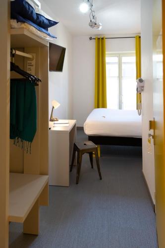 a small room with a bed and a desk with a lamp at Hotel Victoria in Strasbourg