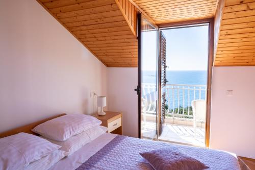 a bedroom with a bed and a balcony with the ocean at Apartments Liza Cavtat in Cavtat