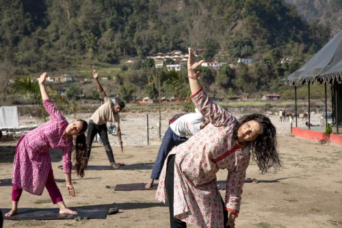 a group of people doing yoga on the beach at Riverside Swiss Camps "Adventure Bear Buddies" in Rishīkesh