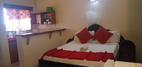 a bedroom with a bed with red and white pillows at Warm and Homely Studio Apartment in Mombasa