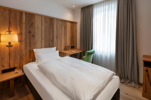 a bedroom with a large white bed and a desk at Eden Hotel Wolff in Munich