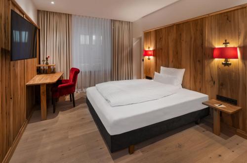 a bedroom with a bed and a desk and a television at Eden Hotel Wolff in Munich