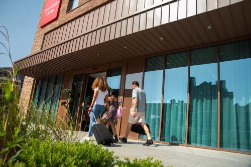 um grupo de pessoas andando fora de um edifício com bagagem em Leonardo Hotel Bristol City em Bristol