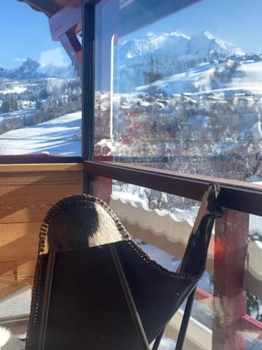 a chair sitting in front of a window with a view at CHALET MONT BLANC in Combloux