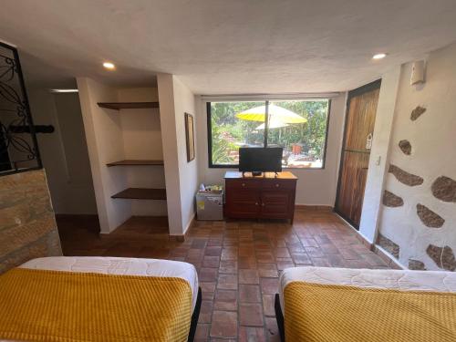 a room with two beds and a television and a window at Hotel Casas de Campo El Ciruelo in San Gil