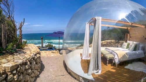 a bed in a glass dome on the beach at Seeplaas Guesthouse in Groot Brak Rivier