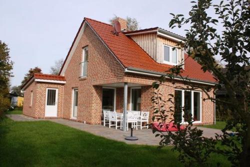 une maison en briques avec une table et des chaises dans une cour dans l'établissement Ferienhaus Bullerbü, à Bedekaspel