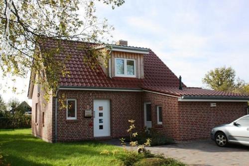 une maison en briques rouges avec une voiture garée devant elle dans l'établissement Ferienhaus Bullerbü, à Bedekaspel