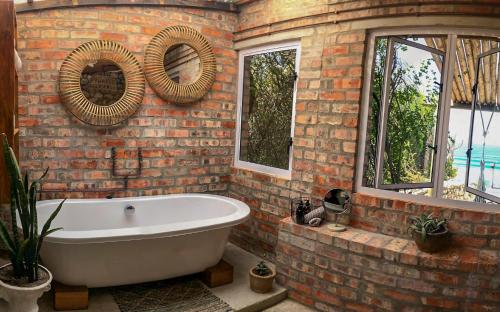 a bathroom with a white bath tub in a brick wall at Seeplaas Guesthouse in Groot Brak Rivier