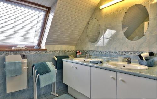 a bathroom with two sinks and two mirrors at Maison sur jardin clos au calme à la campagne et proche des plages in Mahalon