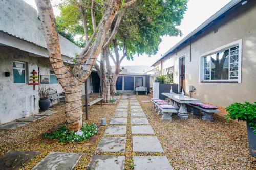 a garden with a tree and benches and a building at Rose Acres Guest House in Parys